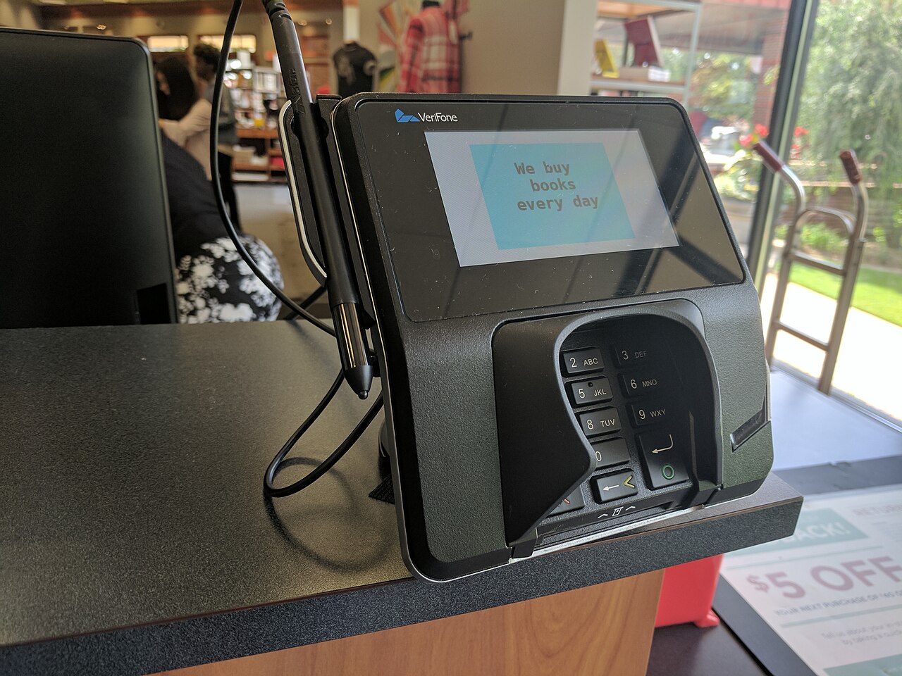 VeriFone touch-screen payment terminal connected to a cash register at a bookstore checkout